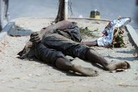 A homeless man sleeps on the street in Dhaka with a bouquet of flowers in his hand (photo: Michael Lund)